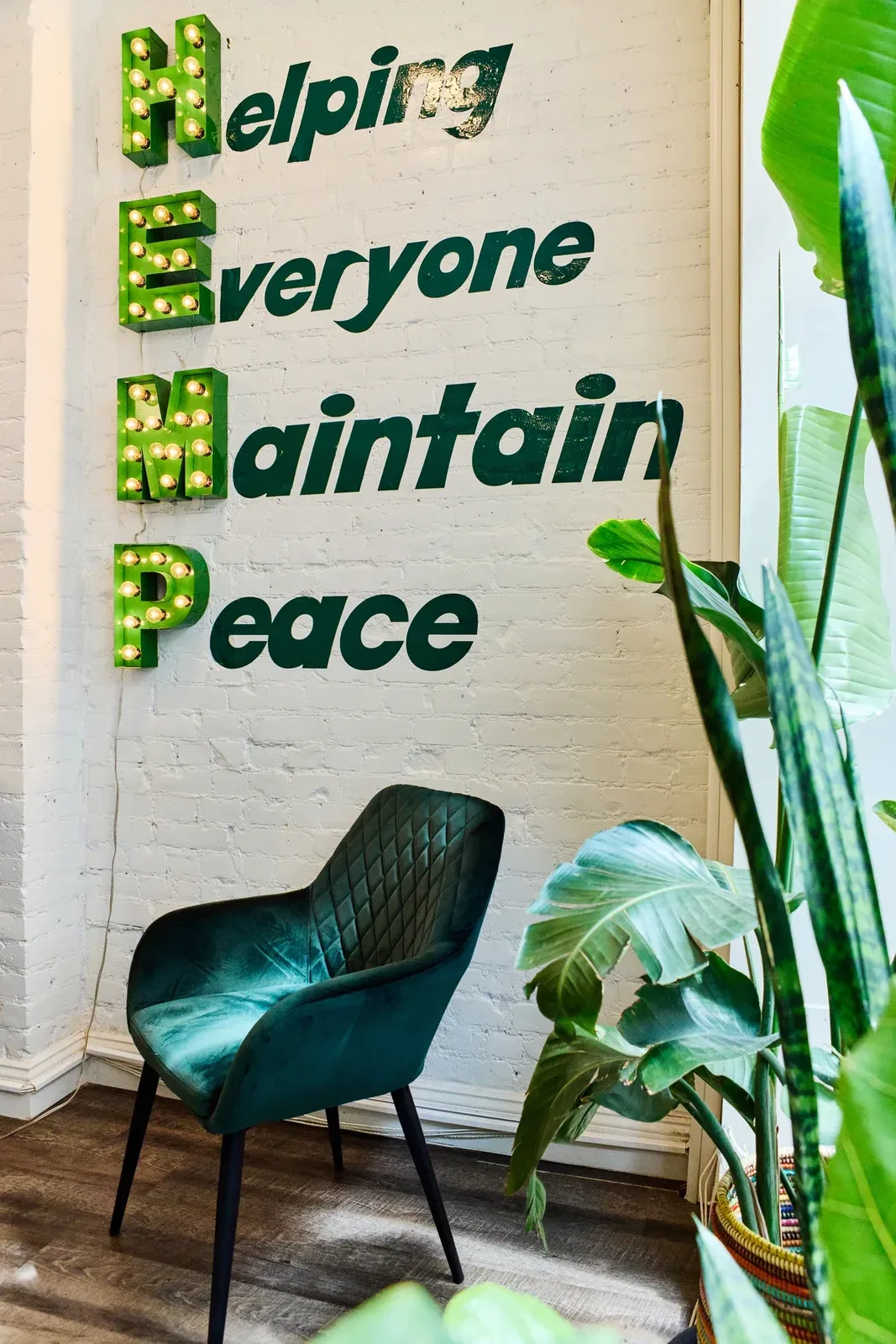 Helping Everyone Maintain Peace wall sign surrounded by leafy plants